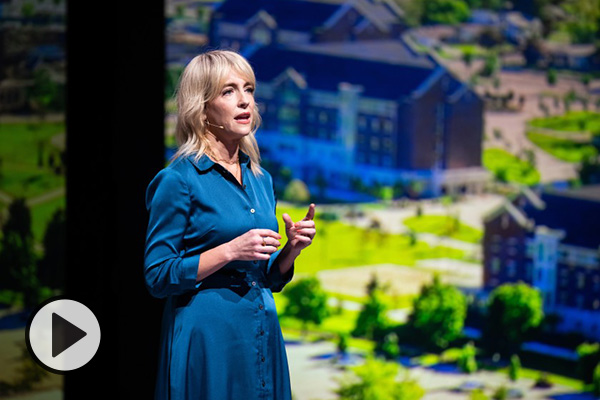 During her recent BYU devotional, Lisa Valentine Clark stands and speaks in front of giant monitors displaying campus scenes.