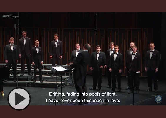BYU Singers performing in a concert hall. Caption reads Drifting, fading into pools of light. I have never been this much in love.