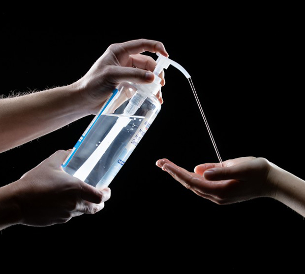In this photo illustration, two hands deliver a healthy stream of hand sanitizer to two other hands cupped and extended below, depicting the idea that alcohol-free hand sanitizer can inactivate the COVID-19 virus in less than 15 seconds. Photo by Jaren Wilkey.