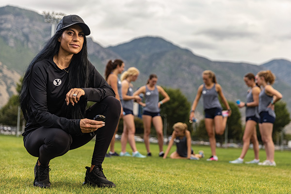 Coach Diljeet Taylor poses on the cross country field with her athletes.