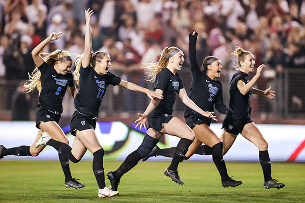 Players from the BYU women's soccer team cheer and celebrate their win.
