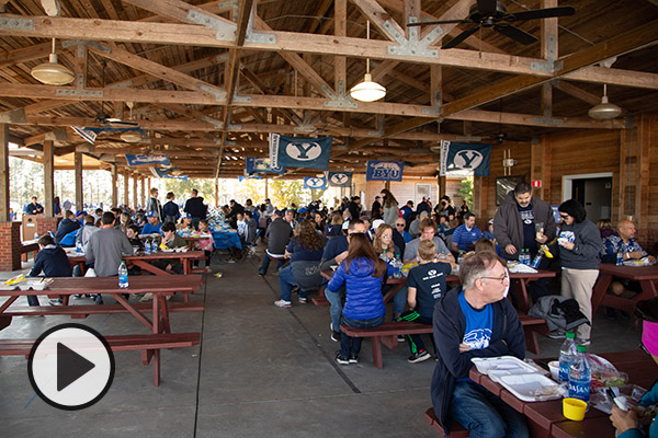BYU fans gather at picnic tables for a tailgate.