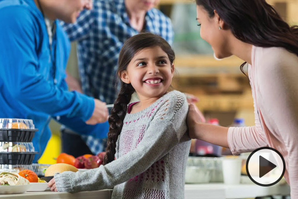 A young girl being served a meal turns to smile at an older woman.