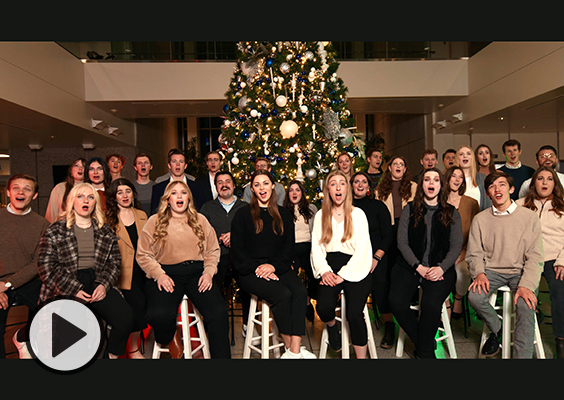 The BYU Singers gather around a Christmas tree to sing.