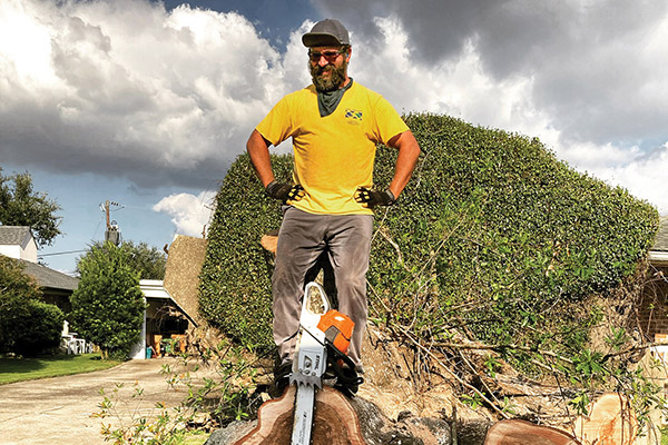 Paul Solouki’s love of service powers him through heat and mess while he cleans up after New Orleans’s latest hurricane. He is pictured near a tree and a chainsaw. Photo courtesy Paul Solouki.