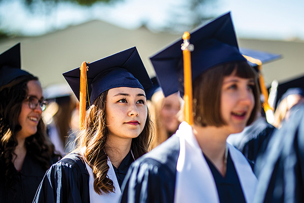 Closeup of BYU grads in blue caps and gowns. Photo by Rebekah Baker.