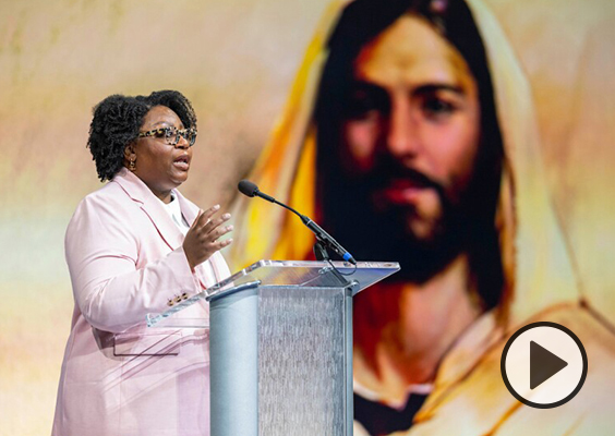 With a photo of Christ in teh background, Sister Tracy Y. Browning stands at a podium for a weekly campus devotional. Photo by Joey Garrison/BYU.