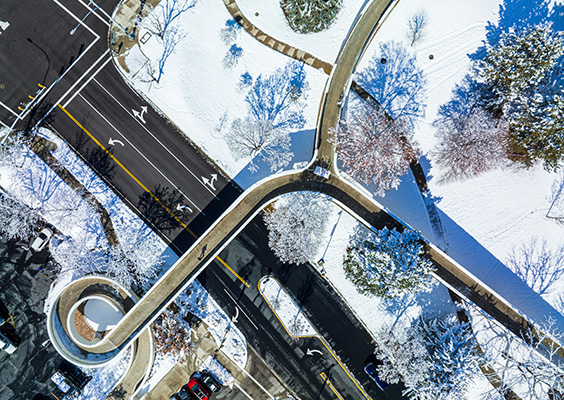 An aerial drone image of the curving walkways and roads of north campus in the snow.
