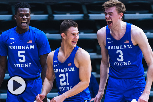 Three BYU basketball in royal blue uniforms celebrate during a game.