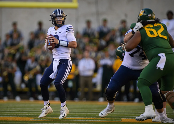 BYU quarterback Jaren Hall in uniform is shown on the field about to throw a pass.