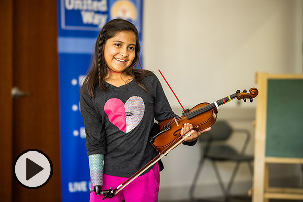 Adia Cardona, a 10-year-old violinist, with her prosthetic limb and a recently engineered device.