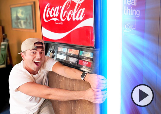 YouTuber Mark Rober pulls back the hidden door to his secret lab to reveal rays of mysterious bright light. It looks like a Coke machine.
