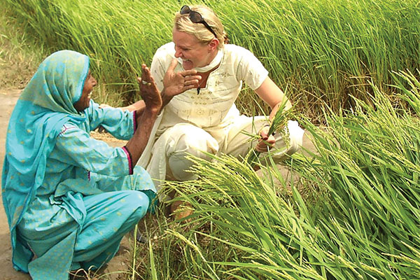 Tiffany Ivins Spence visits with a Pakistani woman near a field with green stalks.