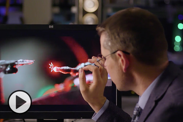 Electrical engineering professor Dan Smalley demonstrates a Star Trek battle scene using screenless display technology with lasers to trap and move an illuminated particle.