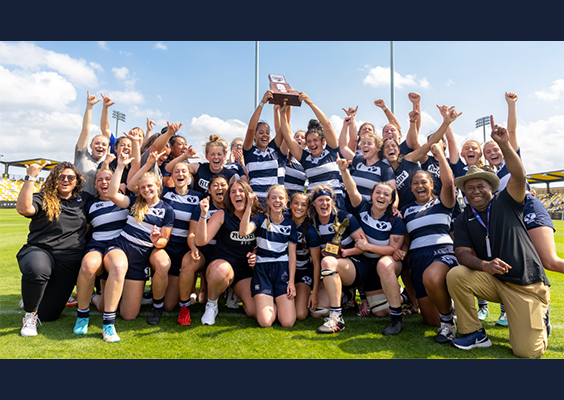 The women's rugby team hoists the championship trophy.