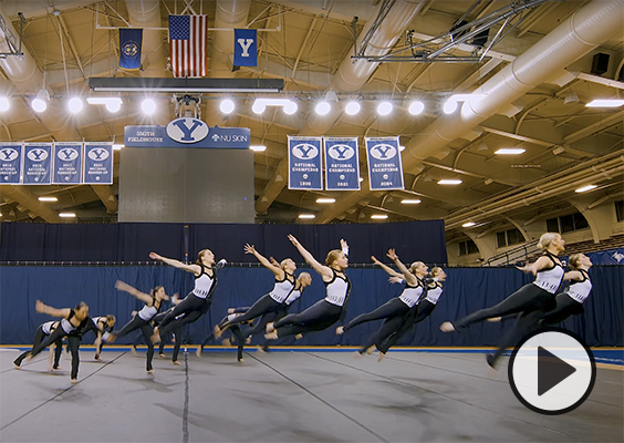 Cosmo is captured spread-eagled in the air above stacked folding tables in the Marriott Center.