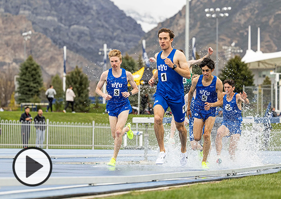 A group of BYU steeplechasers race through water, Kenneth Rooks leading the way.