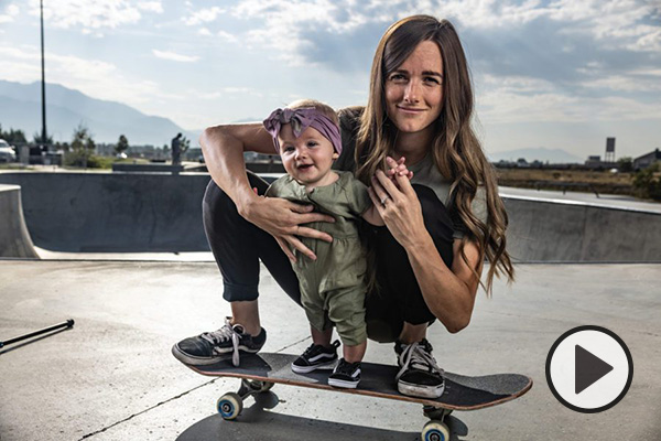 Xan Marcucci and her daughter Ellie both balance on the same skateboard near the concrete ramps of a skating park. Photo by Bradley Slade.