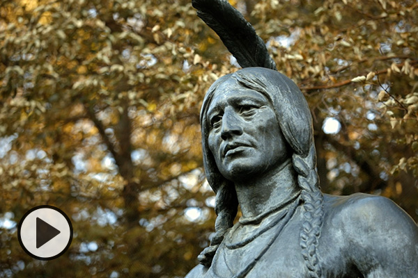 Detail of a BYU campus sculpture of Chief Massasoit, fall leaves in the background.