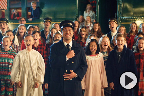 BYU Vocal Point singers in railroad attire join with a children's choir in Christmas pajamas.