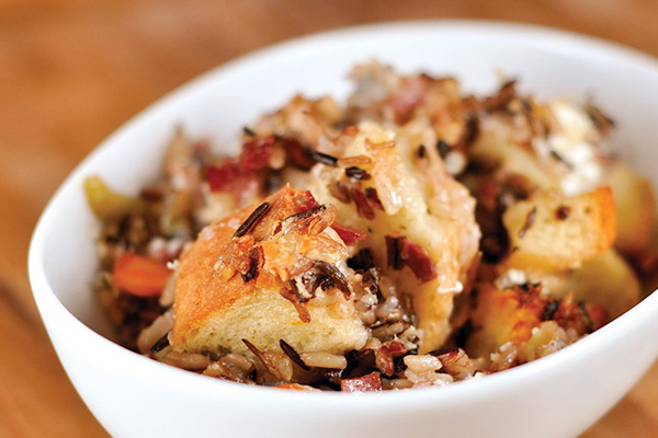 A photo of wild rice and creamy goat cheese stuffing in a white bowl.