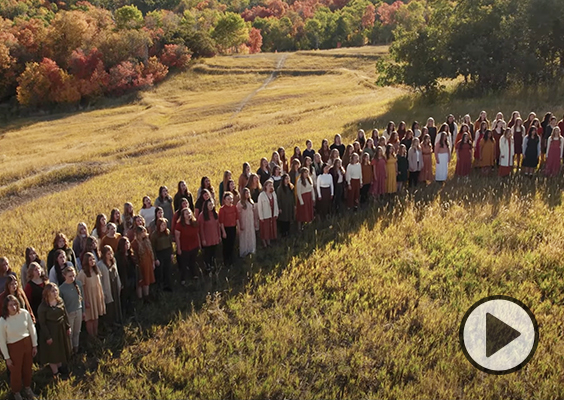 BYU Women’s Chorus sings in an alpine meadow surrounded by trees in fall colors.