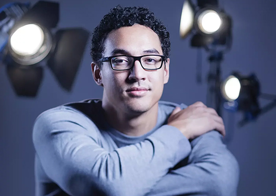 A portrait of actor Langi Tuifua in front of theater lights. Photo by Bradley Slade.