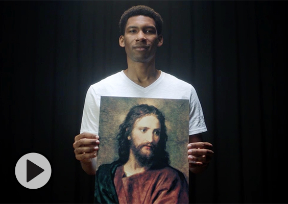An actor portraying a young Elder Peter Johnson holds a large image of Jesus Christ.