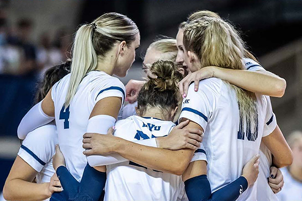 BYU women's volleyball players huddle together during a match.