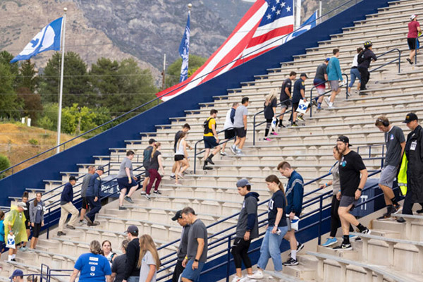 Participants in a Sept. 11 tribute at the stadium trek up and down the stairs. Both a BYU and a U.S. flag wave in the background. Photo by Jaren Wilkey.