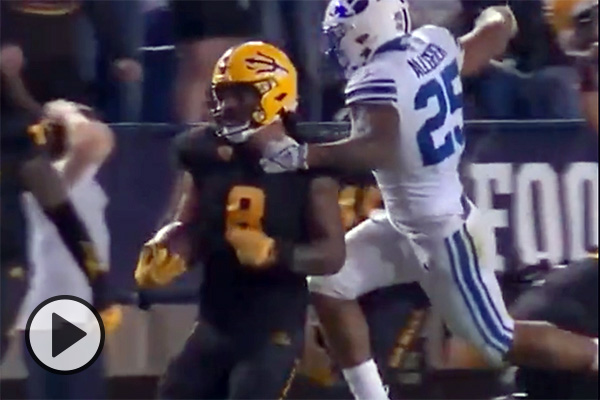 Running back Tyler Allgeier jumps up to punch the ball away from a Arizona State defender who had just intercepted a BYU pass.