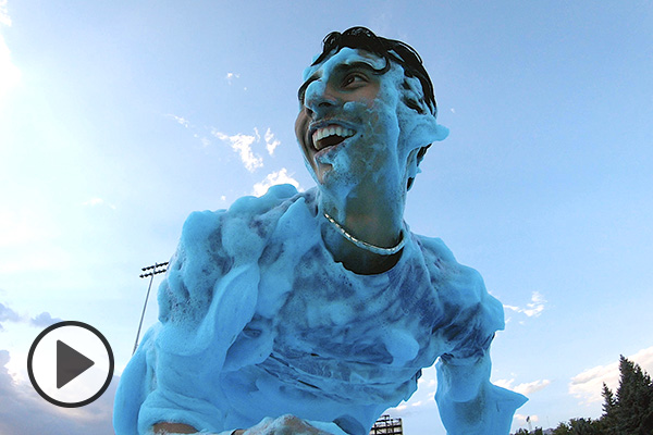 A smiling male student is covered in light blue foam.